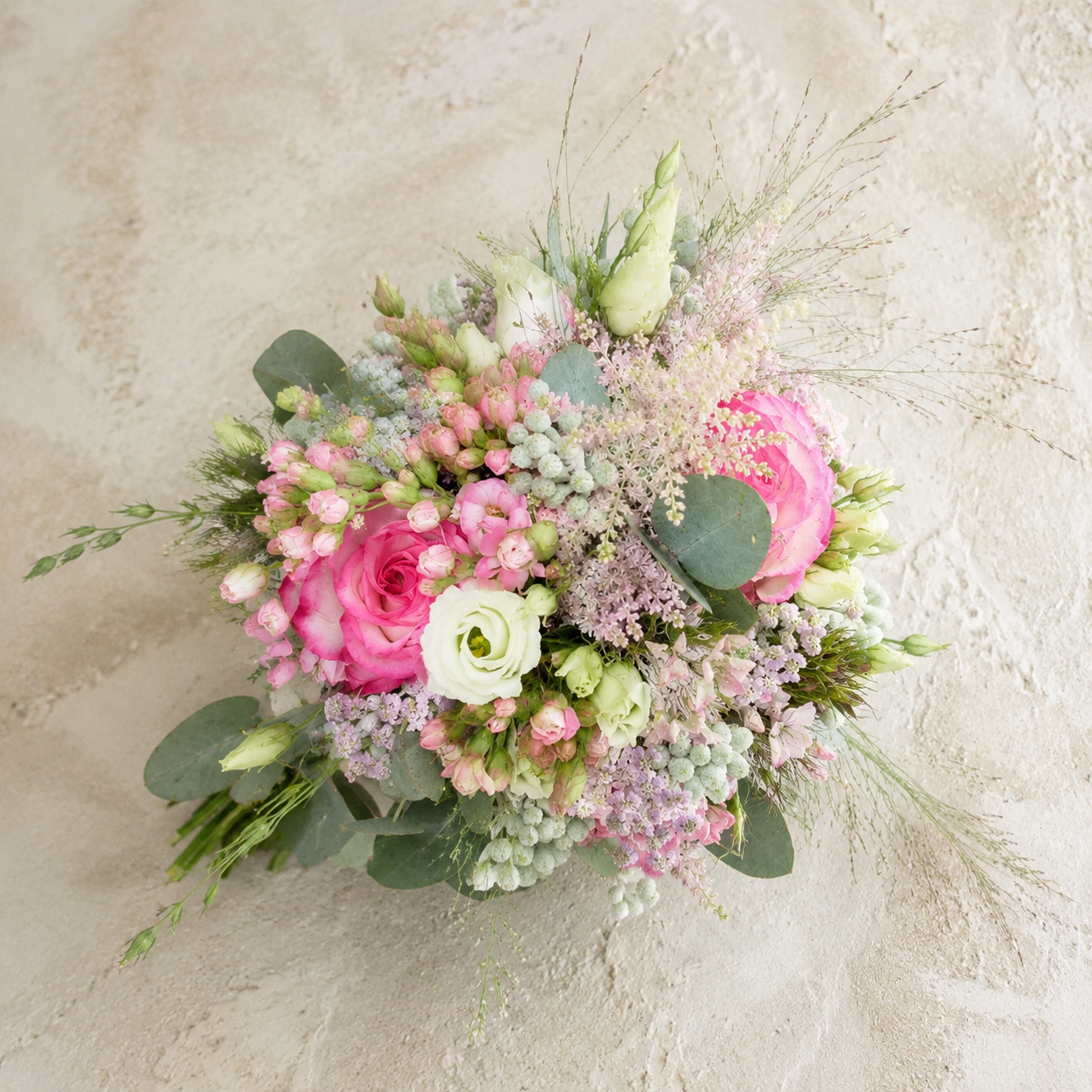 Zart gebundener Brautstrauß in Rosa und Weiß mit Rosen, Lisianthus, Gräsern und Eukalyptus